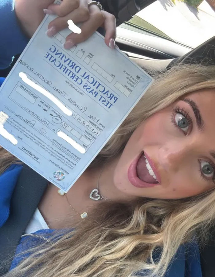 Princess Andre happily holding her practical driving test pass certificate inside a car after buying a $13,000 vehicle.