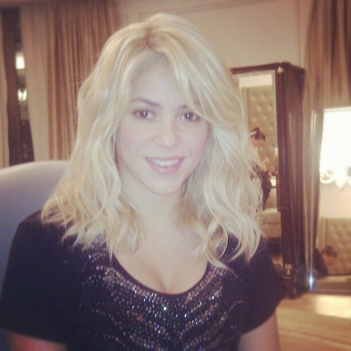Blonde woman smiling indoors wearing a black top with sequins in a vintage celebrity Instagram post.