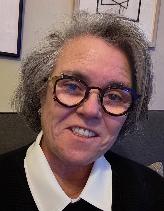 Rosie O'Donnell wearing glasses and a white collar shirt, showing dramatic Mounjaro weight loss transformation.