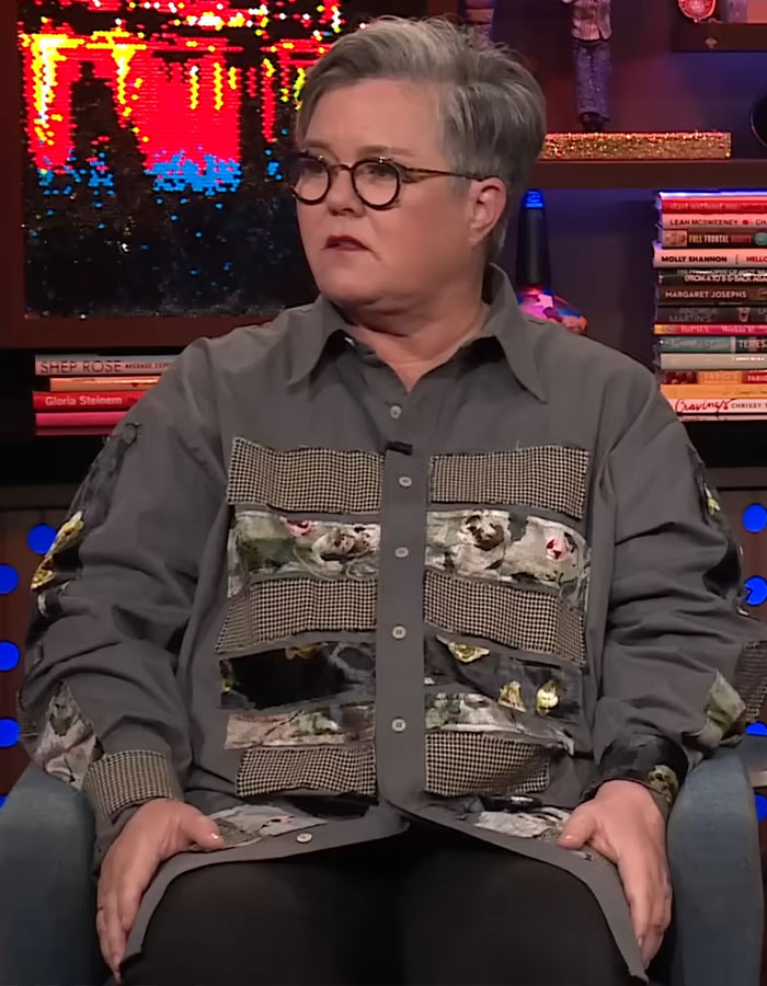 Rosie O&rsquo;Donnell seated in a patterned gray shirt, wearing glasses, showcasing dramatic Mounjaro weight loss on a talk show set.