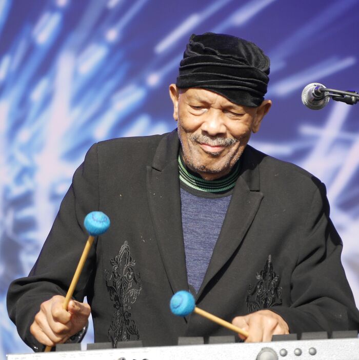 Elderly musician playing percussion with mallets during live performance of notable people who passed away in 2025