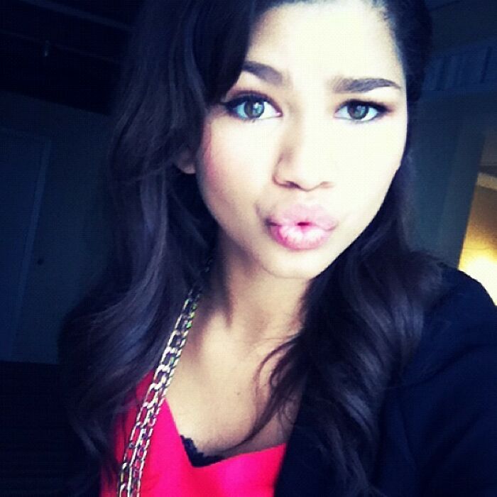 Young woman with long dark hair making a pouty face in a selfie, representing celebrities Instagram posts from back in the day.