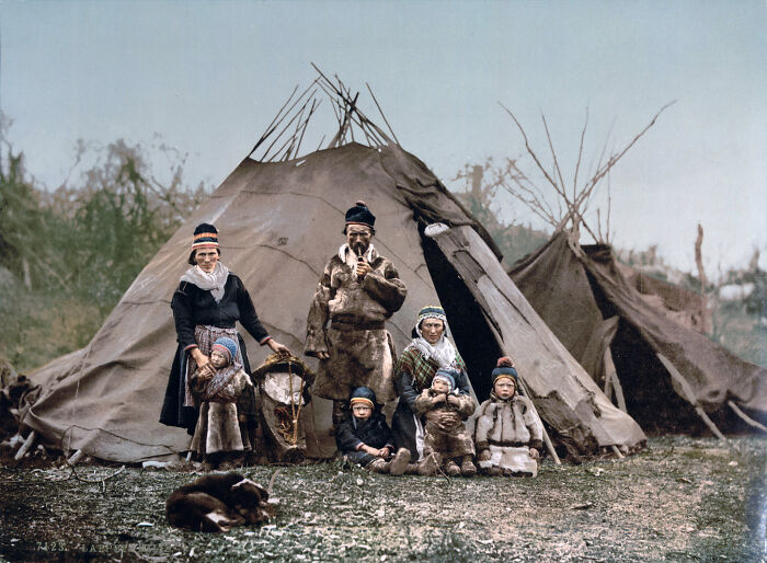 Colorized photo of a family in traditional clothing outside a tipi, revealing the world's vibrant cultural past.