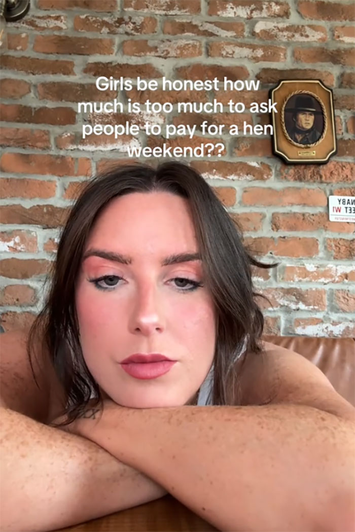 Young woman resting on her arms with text asking how much is too much to pay for hen parties on brick wall background.