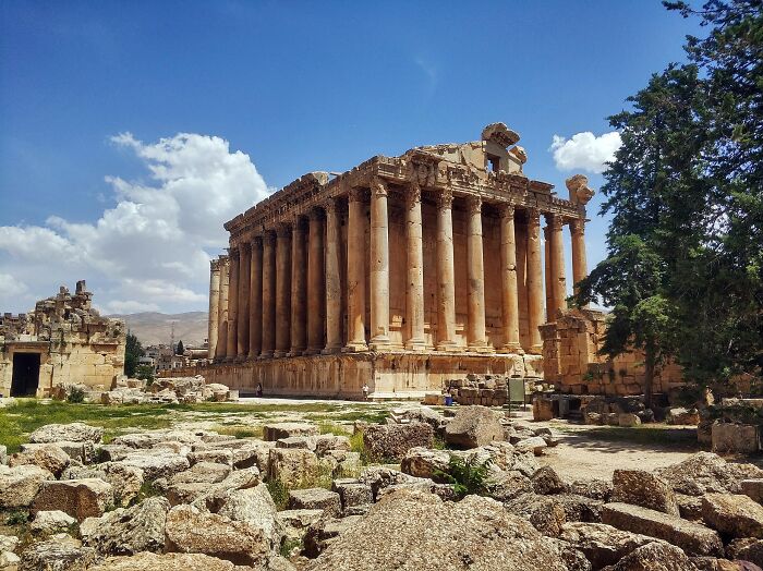 Ancient stone temple with tall columns among ruins under blue sky, showcasing hidden UNESCO gems and historic architecture.