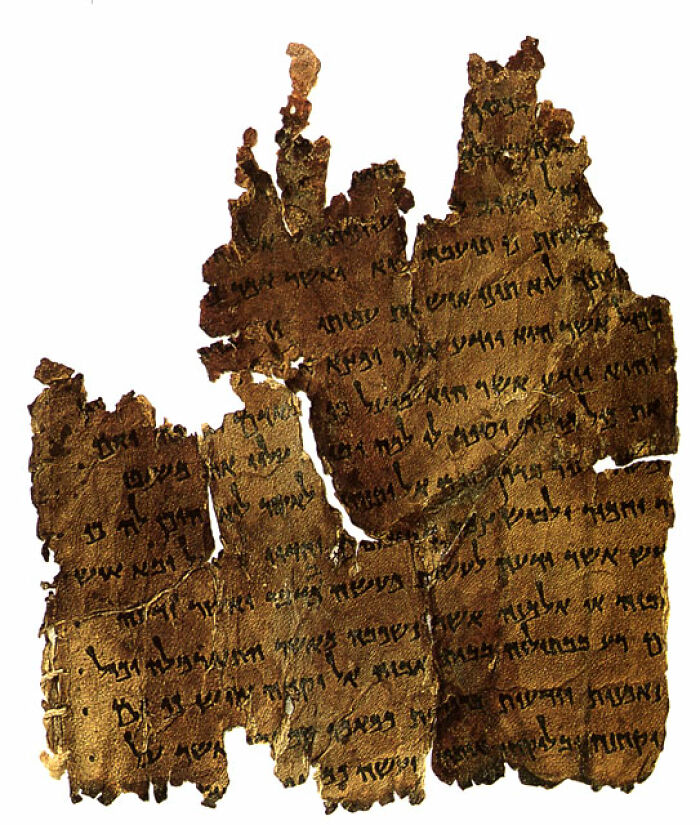 Ancient archeological discovery showing a fragile, partially preserved manuscript with faded script on brown parchment.