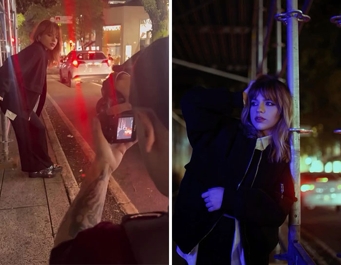 Photographer capturing behind the scenes of a night photoshoot with a model posing on a city street and by a pole.
