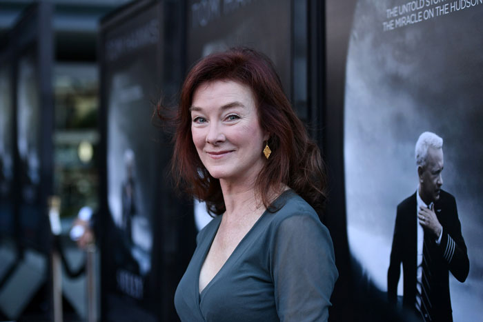 Actress known for Desperate Housewives and Young Sheldon smiles at event wearing blue dress and gold earrings.