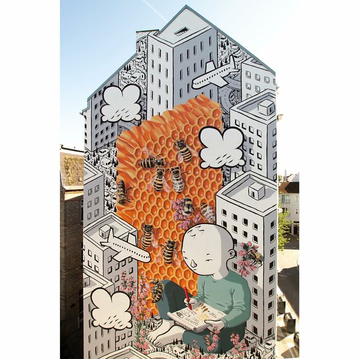 Mural by Italian artist blending city walls with whimsical worlds featuring bees, honeycomb, and a contemplative figure.