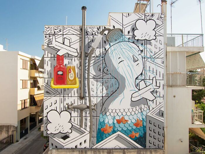 Mural by Italian artist depicting a whimsical figure with a shower on a city wall among illustrated buildings and airplanes.