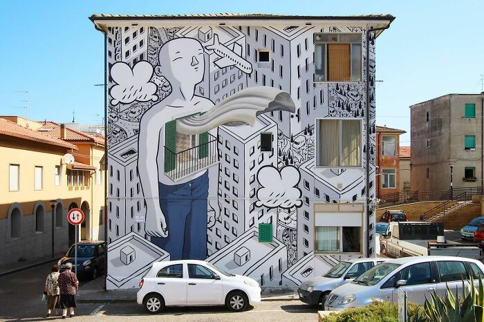 Large mural on a city wall by an Italian artist, depicting a surreal figure in a whimsical urban landscape with flowing shapes.