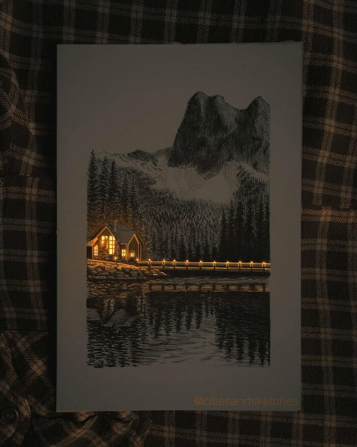 Pen and ink drawing by Ukrainian artist depicting a glowing cabin and bridge scene reflected in a lake at night.