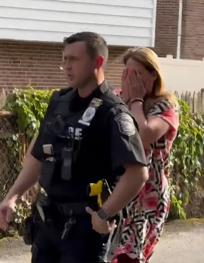 Police officer escorting a distressed woman during arrest related to road rage incident with car vandalism.