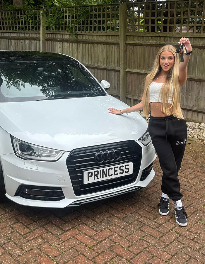 Princess Andre, 17, holding car keys next to her white Audi with personalized plate in a driveway setting.