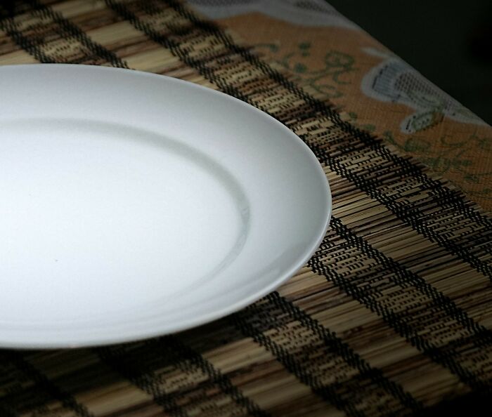 Empty white plate on a woven placemat, illustrating shocking experiences people have lived through moments.
