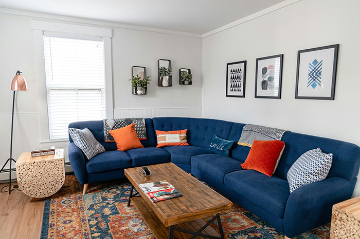 Cozy living room with blue sectional sofa and colorful pillows, perfect for Airbnb stays and guest comfort.