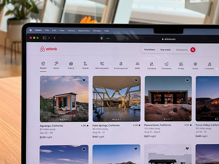 Airbnb listings on a laptop screen showing house options and prices amid a potential host price increase.
