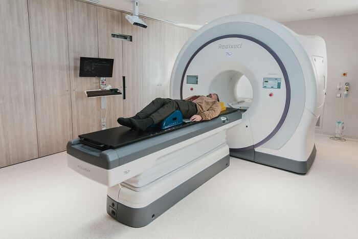Person undergoing a medical scan inside a Radixact machine, showcasing unusual finds shared by doctors and morticians.