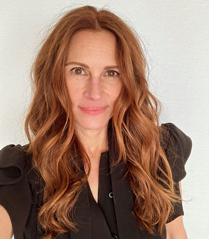 Female celebrity with long wavy red hair and brown eyes, wearing black top, related to hygiene habits controversy.