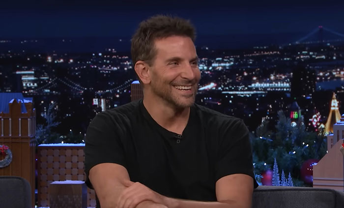 Actor in a black shirt smiling during a nighttime talk show discussing celebrities with gross hygiene habits.