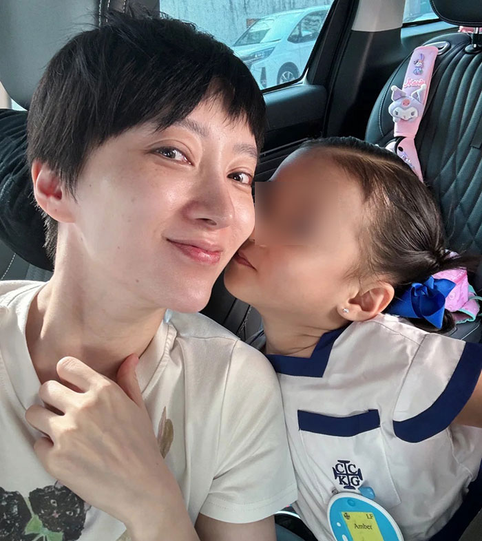 Mother and young daughter sitting inside a car, with the child wearing a preschool uniform and a blue hair bow. Mother and young daughter sitting inside a car, with the child wearing a preschool uniform and a blue hair bow.