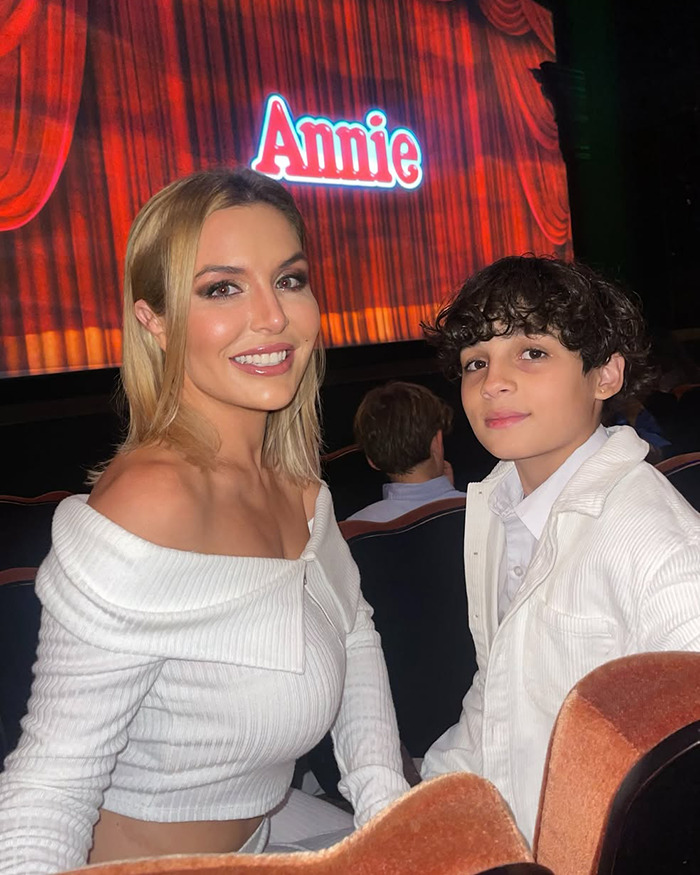 Woman and young boy seated in theater with Annie play curtain, highlighting son took own life and mom raising funds to freeze body. Woman and young boy seated in theater with Annie play curtain, highlighting son took own life and mom raising funds to freeze body.