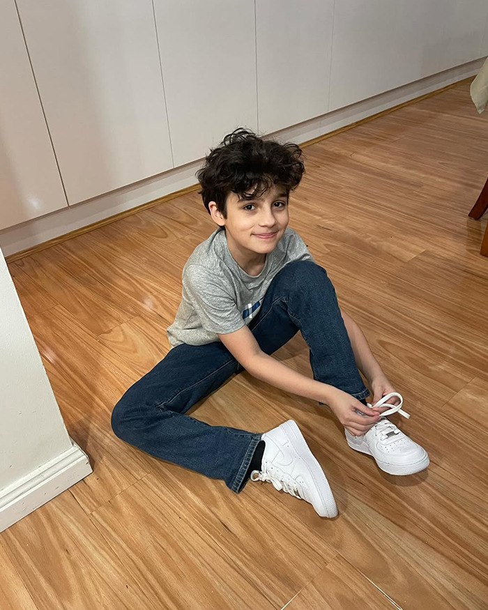 Young boy sitting on wooden floor tying white sneakers, related to fundraising to freeze body after 13YO son took his own life. Young boy sitting on wooden floor tying white sneakers, related to fundraising to freeze body after 13YO son took his own life.