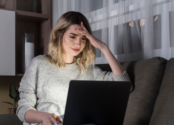 Young graphic designer looking stressed while working on a laptop at home, facing agency work theft issues.