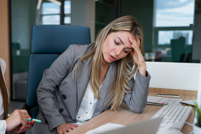 Frustrated graphic designer at office desk reviewing work, representing agency stealing years of graphic designer&rsquo;s work.