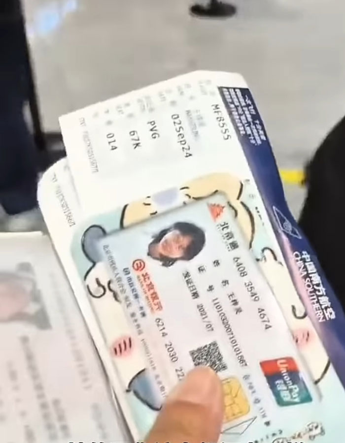 Passenger holding ID card and boarding pass at airport after facial recognition failed due to makeup removal request.