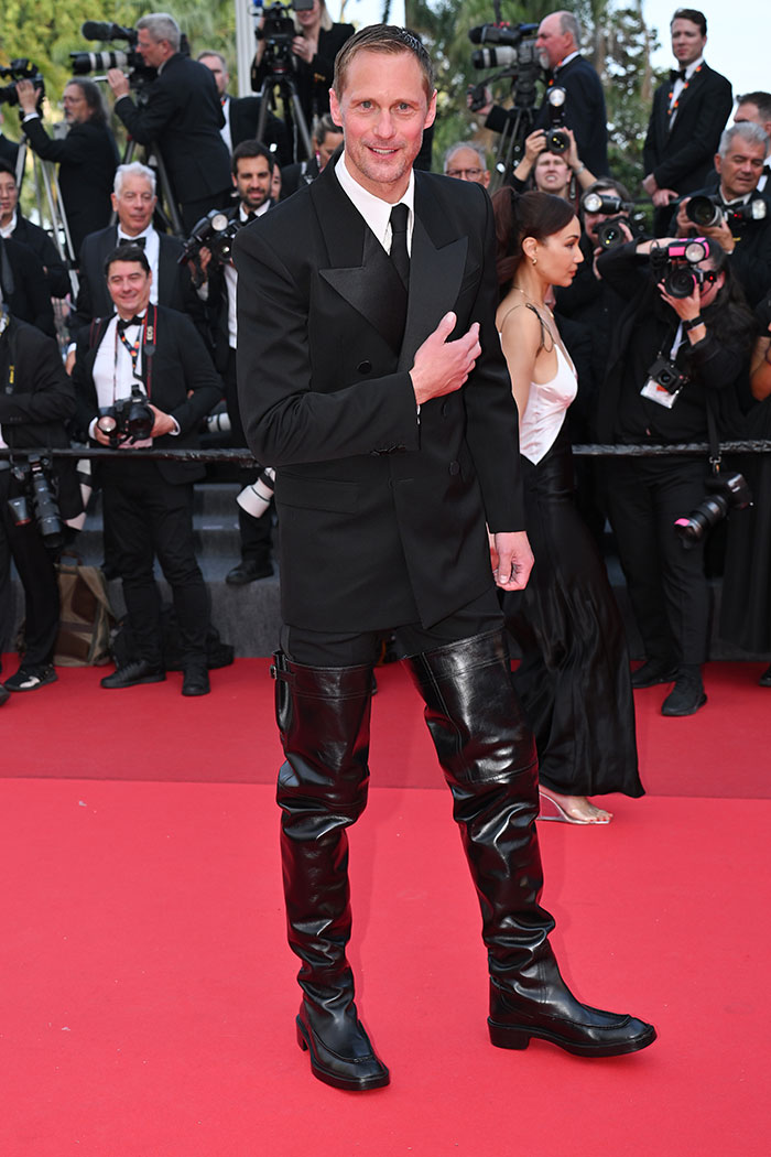 Man wearing oversized leather thigh-high boots and black tuxedo on Cannes Film Festival red carpet, fashion disaster moment