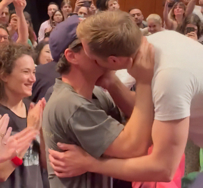 Two men kissing passionately as a crowd applauds, highlighting a Harry Potter star in an X-rated gay film scene.