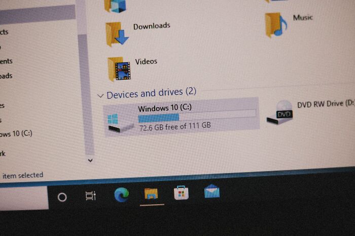 Windows file explorer showing hard drive and DVD RW drive icons while tech guys fix a customer's computer.