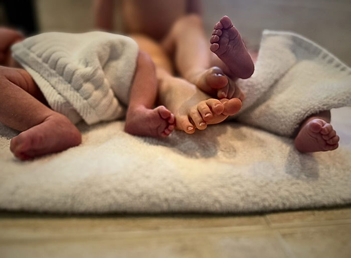 Newborn twins' feet peeking out from soft blankets, symbolizing challenges of potty training after birth. Newborn twins' feet peeking out from soft blankets, symbolizing challenges of potty training after birth.