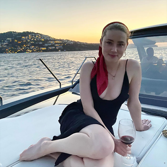 Amber Heard relaxing on a boat at sunset, highlighting Amber Heard net worth timeline and her changing fortune.