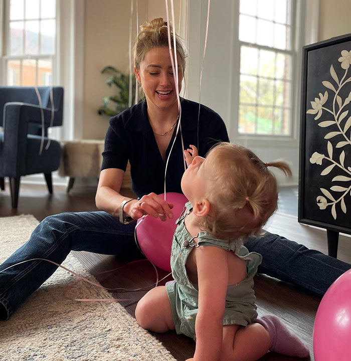 Amber Heard playing with toddler at home, facing public reaction after twins' birth and potty training challenges. Amber Heard playing with toddler at home, facing public reaction after twins' birth and potty training challenges.