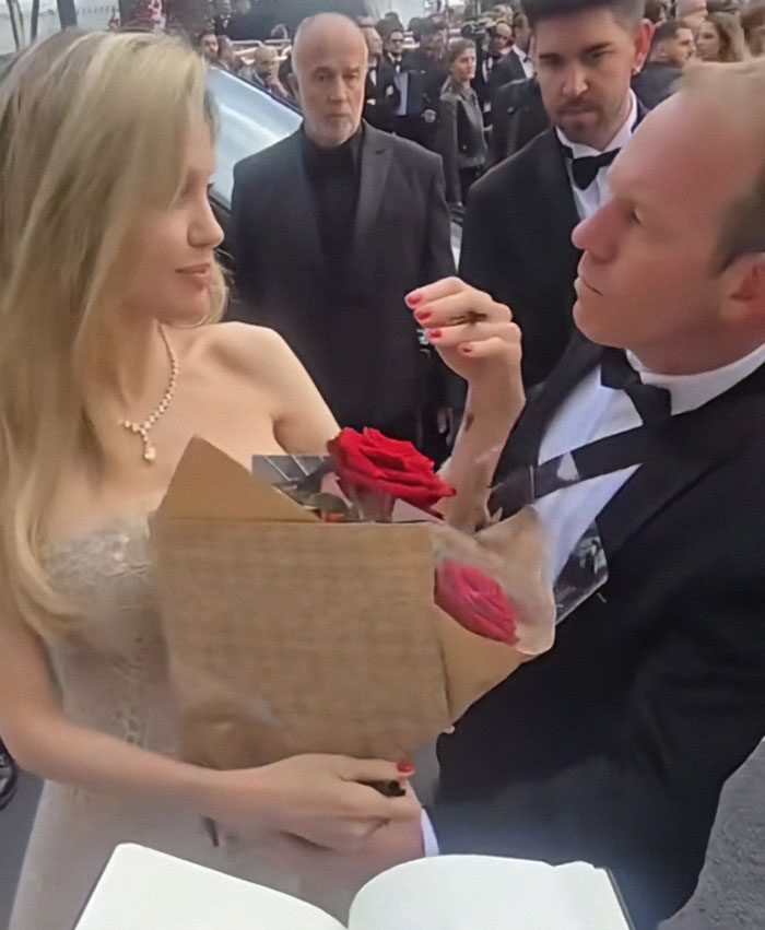 Angelina Jolie holding roses with bodyguard, captured in a moment raising concerns over their interaction.