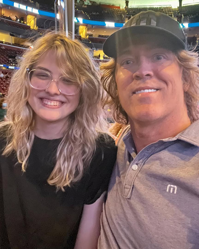 Anna Nicole Smith's look-alike 18-year-old daughter smiling with a man in a casual indoor arena setting.