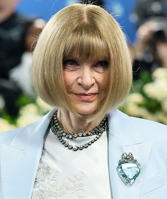 Woman with a blonde bob hairstyle wearing a light blue blazer and jeweled necklace at the Met Gala event.