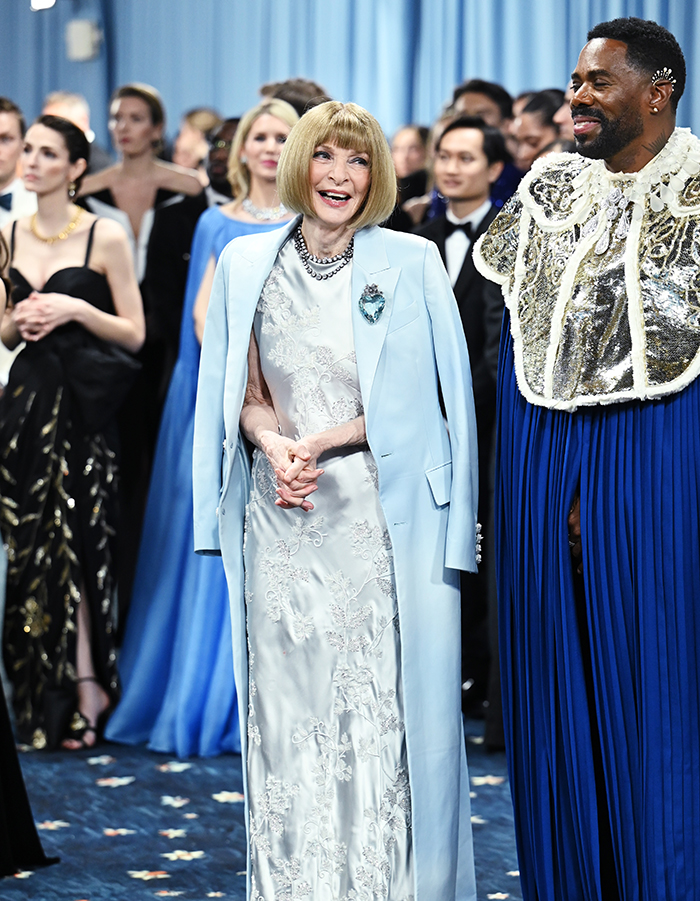 Anna Wintour at the Met Gala wearing a light blue dress amidst attendees, sparking dress stain gossip and firing rumors. Anna Wintour at the Met Gala wearing a light blue dress amidst attendees, sparking dress stain gossip and firing rumors.