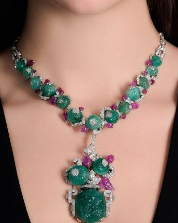 Intricate necklace featuring carved green gemstones and purple accents, showcasing archeology and art through ancient craftsmanship.