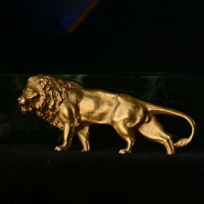 Golden lion sculpture representing an archeological and art wonder displayed against a dark background.