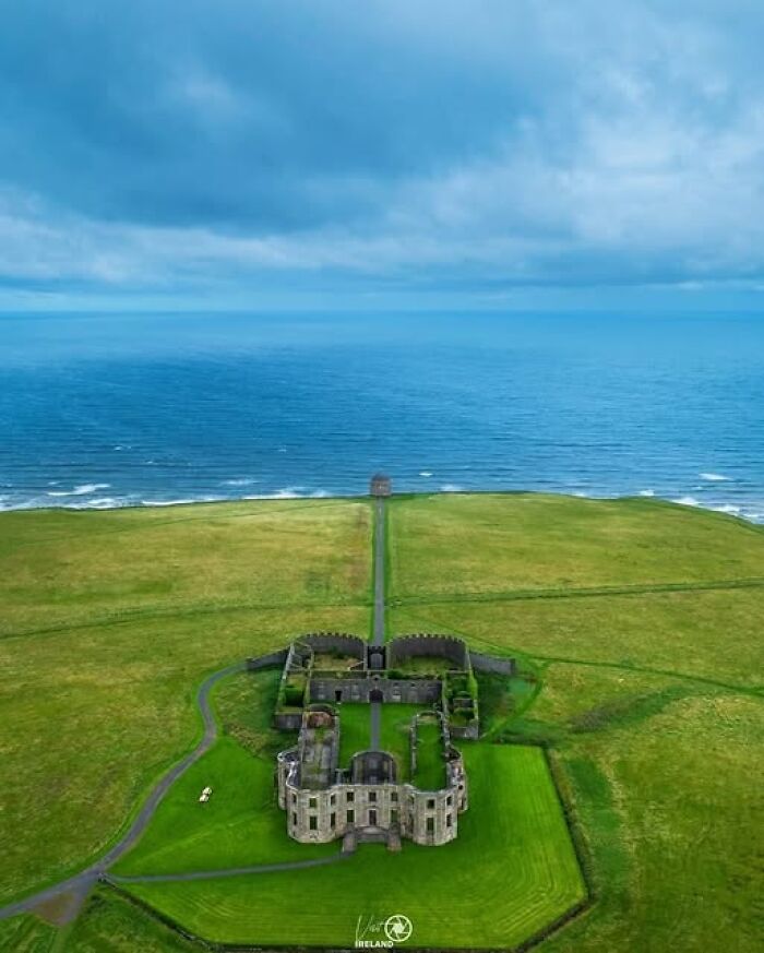 Aerial view of an archeological site and ruins on a green coastline showcasing art and historical architecture.