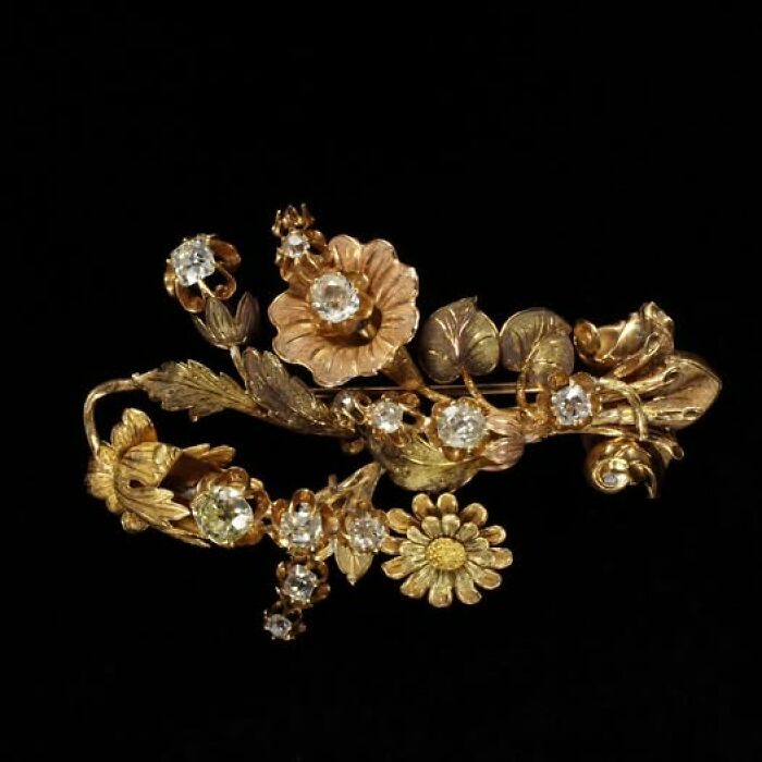 Intricate gold floral brooch with diamond accents, showcasing archeology and art in detailed ancient craftsmanship.