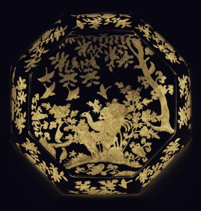 Ornate octagonal artifact featuring detailed gold leaf archeology and art with birds and floral motifs on a dark background