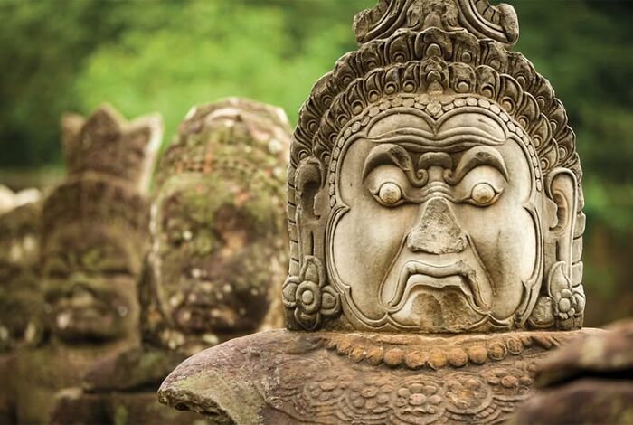 Ancient stone sculptures with detailed carvings in a lush outdoor setting showcasing archeology and art wonders.