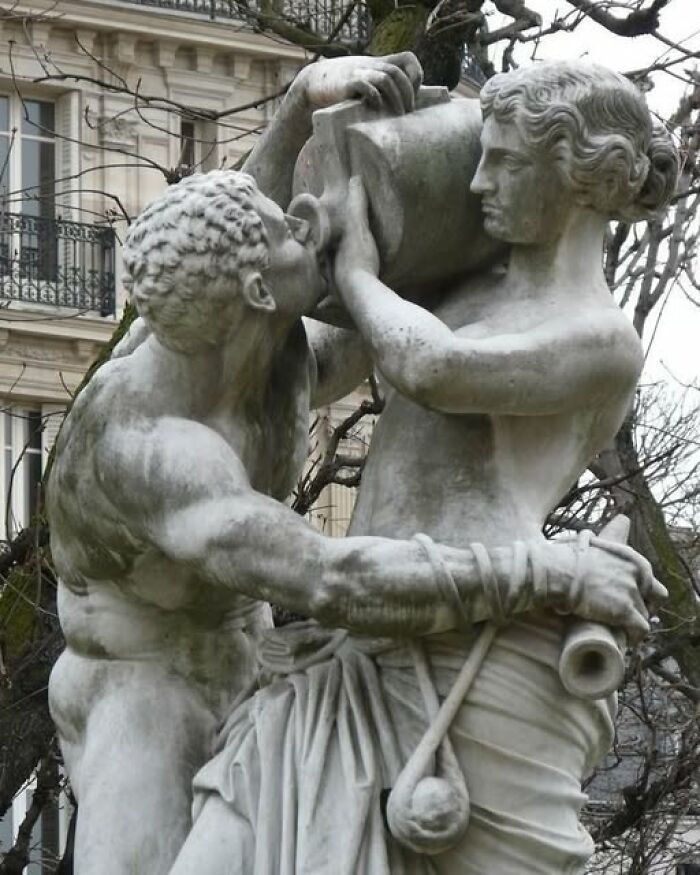 Marble sculpture depicting two figures in dynamic pose, showcasing archeology and art in historic outdoor setting.
