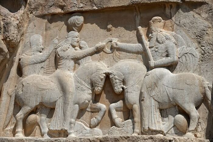 Ancient stone relief depicting figures and horses, showcasing archeology and art in historic archeological wonders.