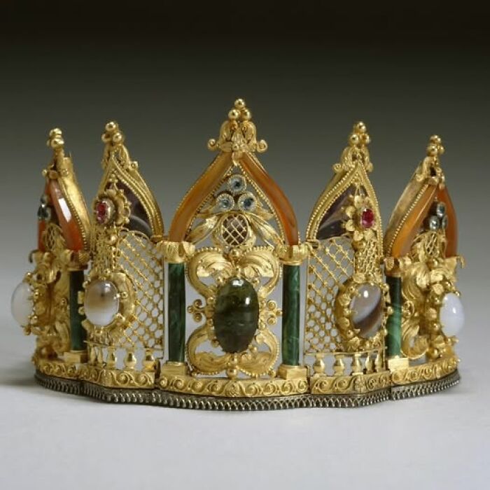 Ornate gold crown with gemstones and intricate designs, showcasing archeology and art in historical craftsmanship.