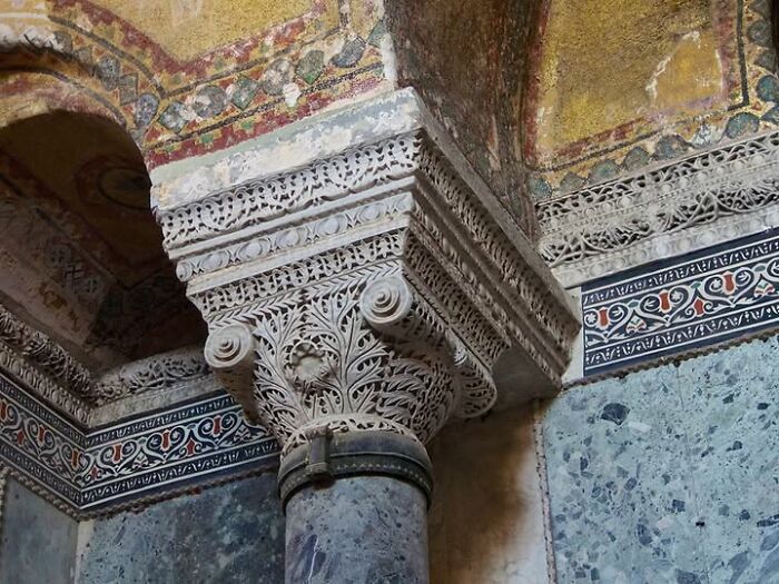 Intricately carved column capital in an ancient structure showcasing archeology and art with detailed patterns and frescoes.